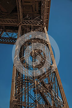 View of one legÃ¢â¬â¢s iron structure of the Eiffel Tower, with sunny blue sky in Paris. photo